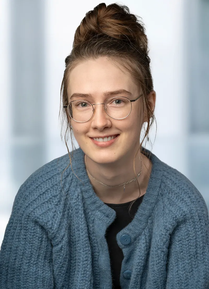 Bewerbungsfoto einer jungen Frau mit blauem Oberteil und Brille